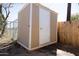 Exterior view of a storage shed in the yard with tan walls, a white door, and surrounded by fencing at 5907 N Azalia St, Casa Grande, AZ 85122