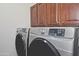 Modern laundry room features dark wood cabinets above modern silver washer and dryer set at 8176 S Pioneer Ct, Gold Canyon, AZ 85118