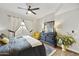 A modern bedroom with a wooden floor, fan, gray comforter, bright yellow chair, and black dresser at 8653 E Royal Palm Rd # 1033, Scottsdale, AZ 85258