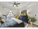 A modern bedroom with a wooden floor, fan, gray comforter, bright yellow chair, and a television on the dresser at 8653 E Royal Palm Rd # 1033, Scottsdale, AZ 85258