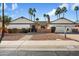 Charming single-story home featuring desert landscaping, brick accents, a two-car garage, and mature palm trees at 10052 N 77Th St, Scottsdale, AZ 85258