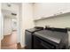 Laundry room with black side-by-side washer and dryer, and white storage cabinets at 10052 N 77Th St, Scottsdale, AZ 85258