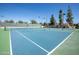 View of a community tennis court on a sunny day with well maintained blue courts and green borders at 10052 N 77Th St, Scottsdale, AZ 85258