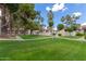 Inviting townhouse community featuring lush green lawns, mature shade trees, and manicured shrubs under a clear blue sky at 10610 S 48Th St # 2001, Phoenix, AZ 85044