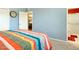 Bright bedroom with a clock on the wall, colorful bedding, and open bathroom and closet doors at 10922 W Peoria Ave, Sun City, AZ 85351