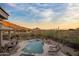 Inviting pool area with lounge chairs, dining table, desert landscape, and beautiful mountain views at dusk at 12276 N 129Th St, Scottsdale, AZ 85259