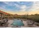 Inviting pool area with lounge chairs, dining table, desert landscape, and beautiful mountain views at dusk at 12276 N 129Th St, Scottsdale, AZ 85259