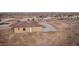 An aerial view shows a desert home with a tile roof, complemented by a spacious driveway and surrounding landscape at 12942 S 218Th Ave, Buckeye, AZ 85326