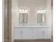 Bright bathroom featuring a double vanity with white cabinets, matching framed mirrors, and modern lighting fixtures at 12942 S 218Th Ave, Buckeye, AZ 85326
