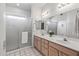 Bathroom featuring dual sinks, framed mirror, and glass door shower, creating a bright and functional space at 14218 W Via Tercero --, Sun City West, AZ 85375