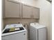 Bright laundry room features a full-size washer and dryer and overhead cabinets at 14610 N 87Th Ave, Peoria, AZ 85381