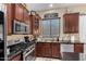 Well-lit kitchen with stainless steel appliances, dark cabinets, and a tile backsplash at 14846 N 145Th Ave, Surprise, AZ 85379