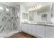 Elegant bathroom featuring double sinks, granite counters, and a glass-enclosed shower with marble tile at 16189 N 137Th Dr, Surprise, AZ 85374
