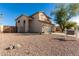 Two story tan home with desert landscaping and large tree in the front yard at 16189 N 137Th Dr, Surprise, AZ 85374