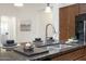Up close is the double sink on the kitchen island with brown granite countertops and bar seating with decor at 16372 W Mulberry Dr, Goodyear, AZ 85395