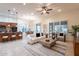 Open-concept living room with tile flooring, ceiling fan, light colored furniture, with the kitchen and dining area visible at 16372 W Mulberry Dr, Goodyear, AZ 85395