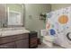 Well-lit bathroom with a decorative mirror, wooden-style floors and a planet-themed shower curtain at 17583 W Paraiso Dr, Surprise, AZ 85387