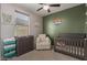 Charming Bedroom featuring a crib, changing table, soft chair, and a decorative green accent wall at 17583 W Paraiso Dr, Surprise, AZ 85387