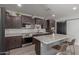 Bright kitchen with a center island, dark cabinetry, stainless steel appliances, and a modern pantry door at 17583 W Paraiso Dr, Surprise, AZ 85387