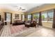 Bright living room featuring a large leather sectional, tile flooring, large windows, and a ceiling fan at 19405 W Oregon Ave, Litchfield Park, AZ 85340
