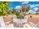 Outdoor patio set surrounded by mature trees, providing a relaxing and scenic setting at 20827 N Stonegate Dr, Sun City West, AZ 85375