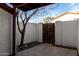 Tiled patio area with a mature tree and gated access, enclosed by privacy walls for outdoor relaxation at 2842 E Beck Ln # 2, Phoenix, AZ 85032