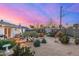 A spacious backyard landscaped with desert flora, featuring a patio dining set under a vibrant evening sky at 2902 E Avalon Dr, Phoenix, AZ 85016
