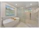 Bright bathroom featuring a soaking tub, a glass block divider, and a walk-in shower at 3500 E Lincoln Dr # 22, Phoenix, AZ 85018