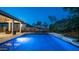 Inviting swimming pool with travertine deck, striped umbrellas, and a well-maintained yard at dusk at 40195 N Hailey Ln, Queen Creek, AZ 85140