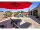 Relax on the lounge chairs under a red umbrella next to the luxurious pool with its built-in waterfall feature at 4426 E Capricorn Pl, Chandler, AZ 85249