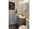 Neutral powder room featuring wood-look flooring, gray vanity, oval mirror, and decorative wall art at 4535 W Cottontail Rd, Phoenix, AZ 85086