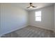 Simple bedroom with neutral carpet, ceiling fan, and a bright window at 57856 W Fulcar Rd, Maricopa, AZ 85139