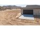 A side view of garage highlighting desert landscape, modern roll-up door, and concrete driveway at 57856 W Fulcar Rd, Maricopa, AZ 85139