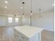 Bright, open-concept kitchen with a quartz island, modern pendant lighting, and wood-look flooring at 57856 W Fulcar Rd, Maricopa, AZ 85139