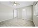 A neutral bedroom offering tiled floors, bright windows, a ceiling fan, and convenient closet and door access at 9066 N Thunderbird Rd, Maricopa, AZ 85139
