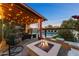 Relaxing outdoor patio with a cozy fire pit, overhead lighting, and backyard pool view at 924 E Whitton Ave, Phoenix, AZ 85014