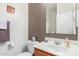 Neat bathroom featuring a white sink and toilet, contrasted with a dark brown accent wall at 1225 N 36Th St # 2091, Phoenix, AZ 85008