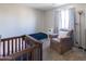 Cozy bedroom featuring a dark wood baby crib, a brown armchair, and soft carpeting at 1349 E Dunbar Dr, Phoenix, AZ 85042
