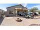 Beautiful backyard with a covered patio, fire pit, seating area, and well-maintained landscaping at 15876 W Alpine Ridge Dr, Surprise, AZ 85374