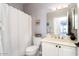 Bright bathroom featuring a vanity with sink, toilet, shower with curtain and large mirror at 15876 W Alpine Ridge Dr, Surprise, AZ 85374