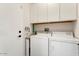 Functional laundry room with white cabinets, washer, and dryer for convenient chores at 15876 W Alpine Ridge Dr, Surprise, AZ 85374