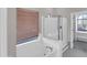 Bright bathroom featuring a soaking tub with a large window and a glass-enclosed shower at 16247 W Desert Mirage Dr, Surprise, AZ 85379