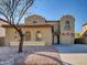 Charming two-story home with a desert landscaped front yard featuring a mature tree at 16247 W Desert Mirage Dr, Surprise, AZ 85379