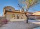 Side view of a two-story home with desert landscaping featuring a mature tree and charming arched windows at 16247 W Desert Mirage Dr, Surprise, AZ 85379