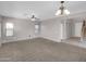 Spacious living room featuring neutral paint, carpet, ceiling fan, and entry to stairs and a hallway at 16247 W Desert Mirage Dr, Surprise, AZ 85379