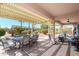 Spacious covered patio with seating and dining areas surrounded by lush greenery at 16495 W Monteverde Ln, Surprise, AZ 85374