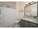 Well-lit bathroom with a granite countertop, vanity, a large mirror, and a shower tub combo with a curtain at 16495 W Monteverde Ln, Surprise, AZ 85374