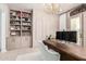 Modern office showcasing custom built-ins, neutral walls, white rug, modern chandelier, and a unique desk at 17336 W Crawfordsville Dr, Surprise, AZ 85388