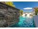 A sparkling pool featuring a stone waterfall and manicured landscaping at 17336 W Crawfordsville Dr, Surprise, AZ 85388
