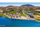A stunning aerial view features a lakefront beach area with picnic spots, sports courts, and lush landscaping surrounded by mountains at 17563 W Summit Dr, Goodyear, AZ 85338